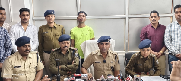 पुलिस अधिकारियों के मध्य में पीछे पर हरा टी शर्ट पहना खड़ा हुआ गिरफ्तार आरोपित।