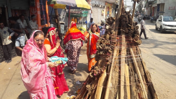 मठ मंदिर चौक के पास होलिका दहनके लिए रखी लकड़ियों व कंडे की पूजन करती हुई महिलाएं।